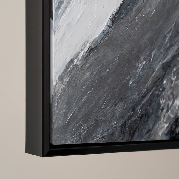 Close-up of a textured abstract painting with a dark gray palette and strokes of silver, framed in a sleek black wooden frame, showcasing the depth and detail of modern wall art