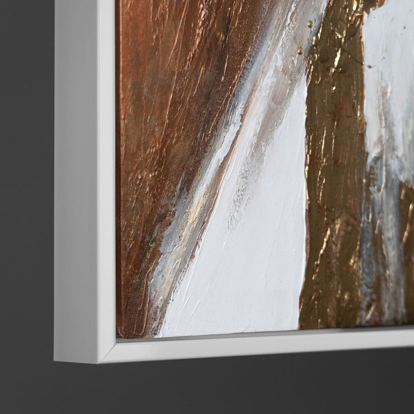 Close-up of a framed abstract painting showcasing a blend of golden highlights with earthy brown and white tones on a textured canvas, emphasizing the richness and depth of the artwork